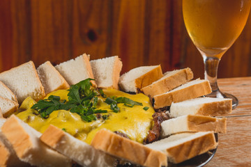 Comida de boteco brasileira picadinho de carne flié ao molho servido com pão em tigela em balcão...