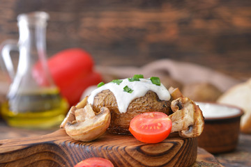 Tasty baked potato with sour cream and mushrooms on table