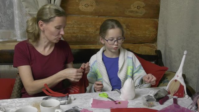 Daughter, mother and grandmother make toys at the table for the New Year holiday. Family evening in the run-up to the holiday three generations of craftswomen make soft toys with their own hands.