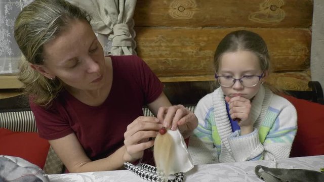 Daughter and mother make toys at the table for the New Year holiday. Family evening in the run-up to the holiday two generations of craftswomen make soft toys with their own hands.