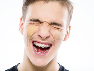 Close-up portrait of a young man with cosmetic cream on his face - isolated on white background