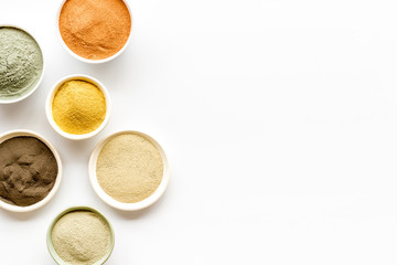 Yellow, red, white, blue and black cosmetic clay on white table top view copy space