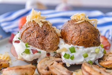 Tasty baked potato with sour cream and mushrooms on plate, closeup