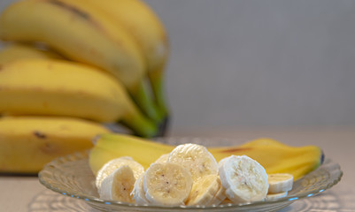 Bananas cut and served on a plate and defocused banana fruits in the background