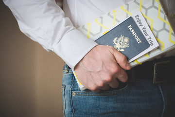 American passport in the hand of a young man. Passport and travel documents. Waiting for a flight at the airport at customs or passport control. Business trip. Open world.