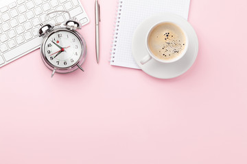 Pink workplace with computer, supplies, coffee and alarm