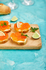 Salmon red caviar in bowl and Sandwiches with on wooden cutting board
