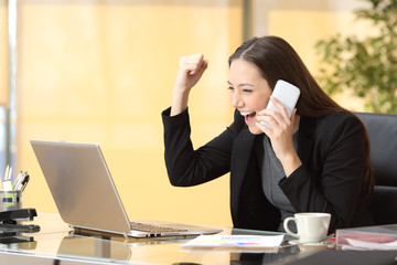 Executive on the phone celebrating news with laptop