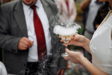 glass of champagne with a dry ice haze in hand
