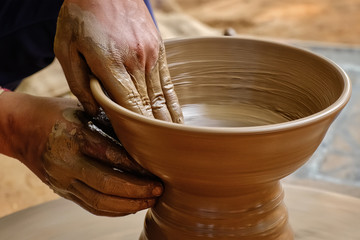 Pottery - skilled wet hands of potter shaping the clay on potter wheel. Pot, vase throwing....