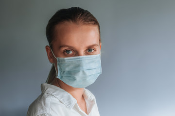 A woman in a medical mask on a light gray background