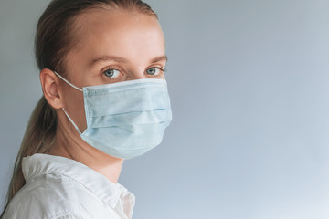 A girl in a medical mask on a gray background. copy space