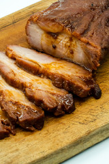 Slices of Roasted BBQ red pork in Chinese style on wooden cutting board isolated on white