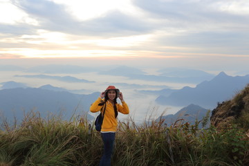A woman standing in the fog and mountain view at Phu Chi Fa National Park, Chiang Rai, Thailand
