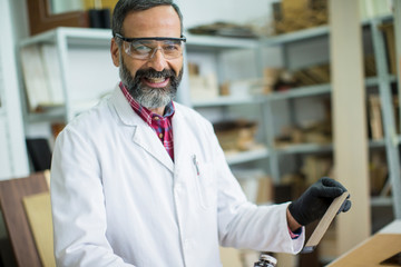 Handsome mature engineer in the laboratory examines ceramic tiles