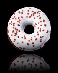 Glazed donut with sprinkles on a black background rotated in three quarters
