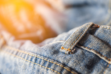 Belt loops of blue jeans with orange light close-up.