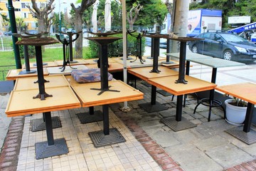 Athens, Greece, April 7 2020 - Tables stacked upside-down outside closed cafe-restaurant after the Coronavirus lockdown.