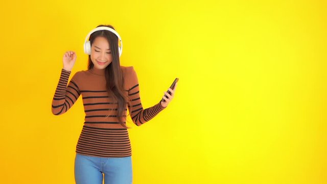 Slomo Asian Girl Listening to Music, Yellow Background. Copy Space for Text.