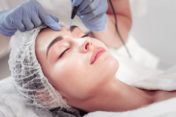 Woman closing eyes while cosmetologist cleansing skin