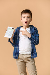 Surprised little boy with calculator on color background