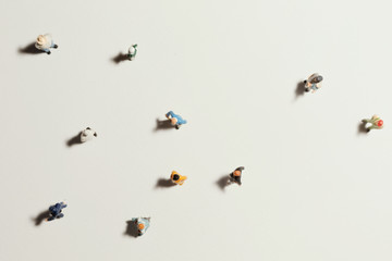 Top view of people (miniature toys) with long shadows keep distance away in public during sunrise or sunset.Social distancing / COVID-19 coronavirus outbreak spreading concept.