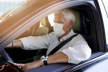 Man driving car and wearing face mask during COVID19 pandemic