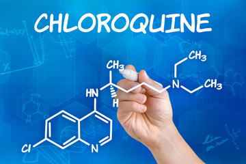 Hand with pen drawing the chemical formula of Chloroquine