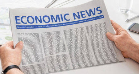 Man reading newspaper with the headline Economic News