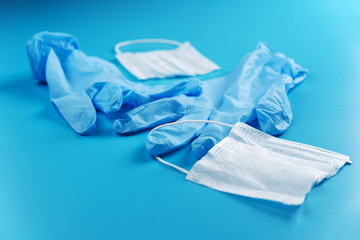 Cut medical mask and crumpled medical gloves on a blue background, end of quarantine.