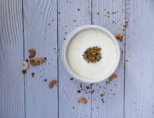 Bowl of cereal matcha oat granola with oat milk, cashew nuts on white wood  Background. vegan food