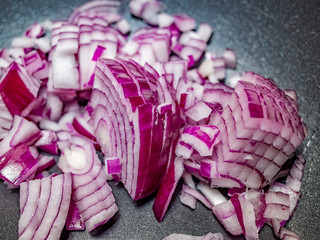 Fototapeta premium Close up and selective focus of sliced red onion (Allium cepa) in a non-stick pan ready for frying off on the hob