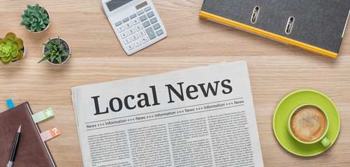 A newspaper on a desk with the headline Local News