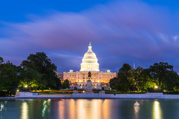 The United States Capitol building at night with reflection in water.