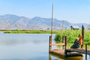 Young tourist standing near the lake. Floating village on the lake. Houses on the lake in the water with floating garden.