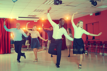 Young people practicing twist movements together at modern dance studio
