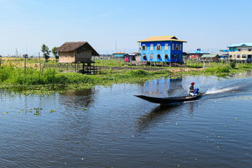 Floating village on the lake. Houses on the lake in the water with floating garden. Wooden boat on...