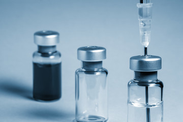 Two medical vial with transparent liquid and medical needle. One medical vial with opaque liquid....