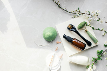 Dermaroller and serum next to an anti aging face cream Beauty industry  Dermaroller for medical micro needling therapy Derma roller mesoroller for mesotherapy on a light background near flowers