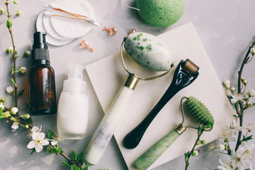 Dermaroller and serum next to an anti aging face cream Beauty industry  Dermaroller for medical micro needling therapy Derma roller mesoroller for mesotherapy on a light background near flowers