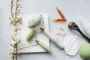 Dermaroller and serum next to an anti aging face cream Beauty industry  Dermaroller for medical micro needling therapy Derma roller mesoroller for mesotherapy on a light background near flowers