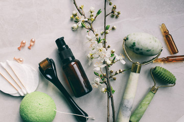 Dermaroller and serum next to an anti aging face cream Beauty industry  Dermaroller for medical micro needling therapy Derma roller mesoroller for mesotherapy on a light background near flowers