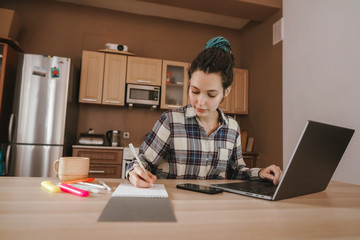 A woman keeps notes in a notebook at a remote job at home. Work from home. Work remotely due to quarantine