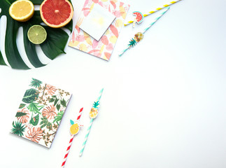 Creative flat lay with Exotic tropical monstera palm leaf and home office stationery on minimal background with summer fruits.