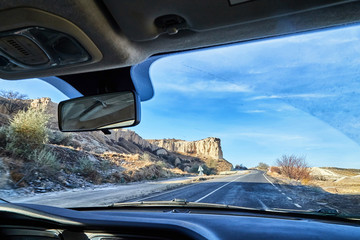 View from car window on the road and strange landscape with a valley, mountains and blue sky with clouds. Landscape through windscreen in Cappadocia in Turkey