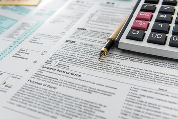 Finance income, time fot tax calculator and pen lying on federal form