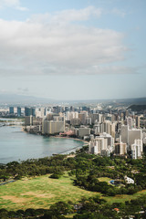 Obraz premium Dramatic views of Waikiki from the Diamond Head Crater Hike summit on a bright but cloudy day.