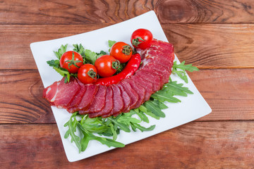 Dried-smoked pork neck, herbs and cherry tomatoes on dish
