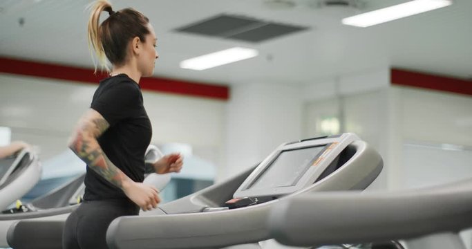 Young woman running on a treadmill at gym. Back view. Woman training at fitness center. Woman exercising cardio workout