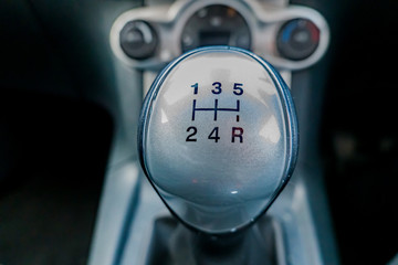Extreme close up and selective focus of manual gear shifter with the background intentionally blurry
